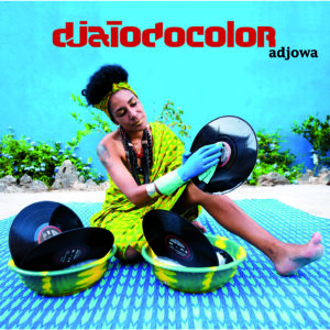 Fotografía de djatodocolor limpiando discos de vinilo en un ambiente colorido, con fondo azul y vegetación, promocionando el EP ‘Adjowa’.