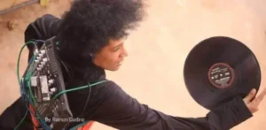 Fotografía artística de djatodocolor sosteniendo un disco de vinilo, conectada a un equipo de audio, capturada por Ramón Codina